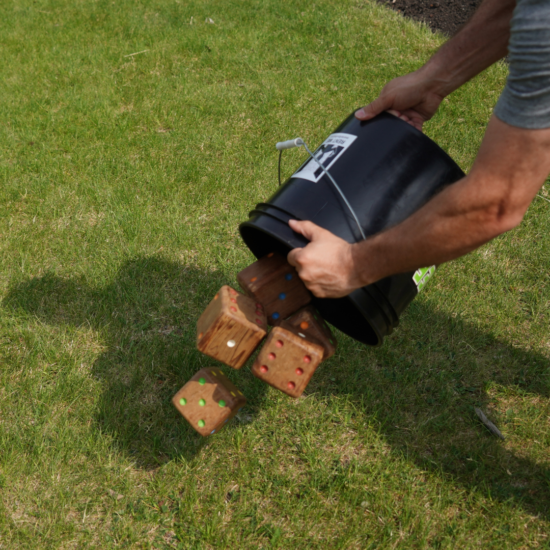 Someone is spilling big wooden dice out of a large black bucket in their hands