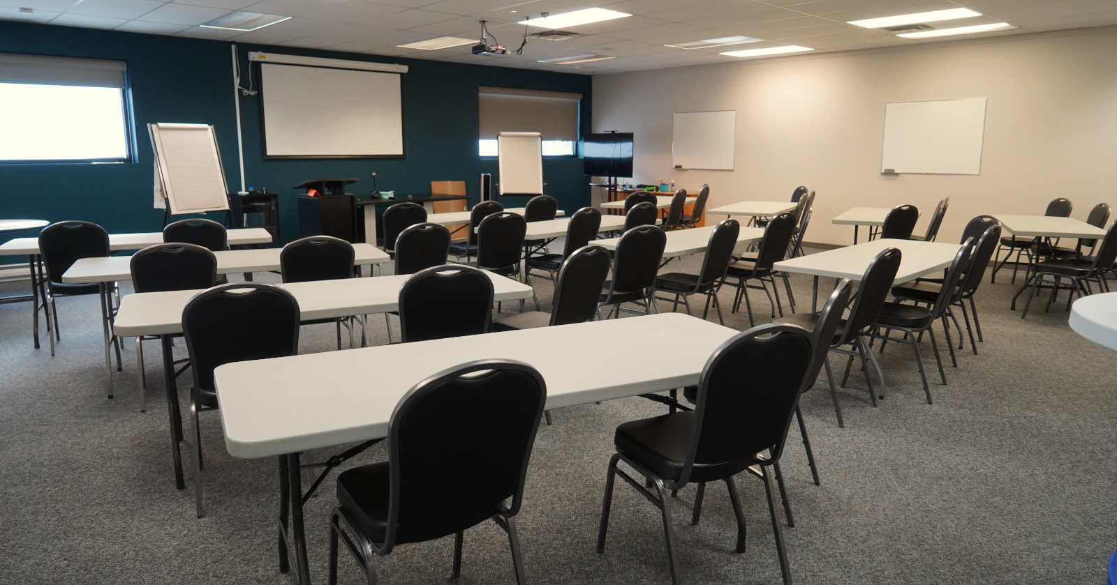 several tables are set up facing the front with two chairs each