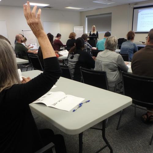 Room A filled with people at tables, one person is raising their hand